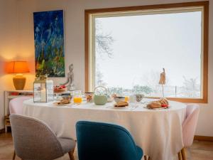 a table with food on it with chairs and a window at La Colline aux Rêves - Chambres d'hôtes in Saint-Franc