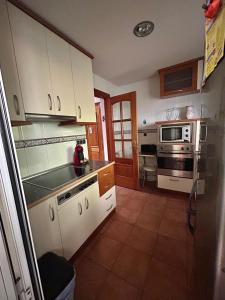 a kitchen with white cabinets and a stove top oven at Buenos Aires apartamento in Guadix