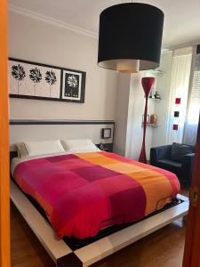 a bedroom with a bed with a red and orange blanket at Buenos Aires apartamento in Guadix