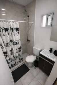 a bathroom with a toilet and a shower curtain at Hospedaje Don Felix in General Acha