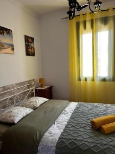 a bedroom with a bed and a window with yellow curtains at La Loma de Alcalá in Arcos de la Frontera