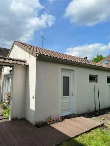 a white house with a door on a deck at Gîte de la Mardelle in Viarmes