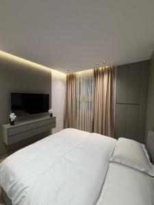 a bedroom with a large white bed and a flat screen tv at Sako Apartaments 2 in Golem