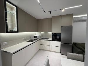 a kitchen with white cabinets and a black refrigerator at Sako Apartaments 2 in Golem