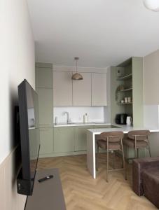 a kitchen with white cabinets and a table and chairs at Calma Apartament Moderato in Starogard Gdański