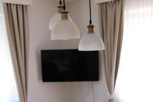 two lights hanging from a wall with a tv at PARK Apartment in Bijeljina