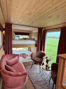 a bedroom with a bed and a couch and chairs at CRASH'NSTAY - Moppie Avenue in Hooge Vaart