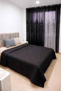 a bedroom with a large bed with a black blanket at Jed appartement in Hammam-Lif