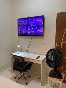 a computer desk with a monitor on a wall with a chair at Casa em Seabra in Seabra
