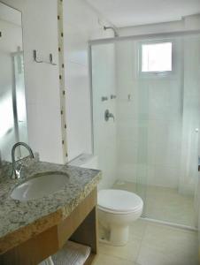 a bathroom with a toilet and a sink and a shower at Villa Maciel Bombinhas in Bombinhas