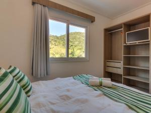 a bedroom with a large bed and a window at Villa Maciel Bombinhas in Bombinhas