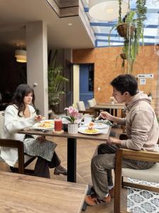 a man and woman sitting at tables in a restaurant at Hotel Casa Agave in Baños