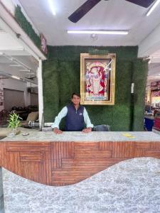 a man standing behind a counter in a room at Shree Sanwariya Hotel in Chittaurgarh