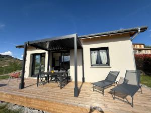 a house with a deck with chairs and a table at The Nest - cosy chalet for two in Jarjayes