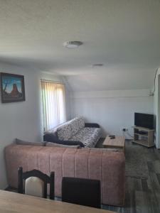 a living room with a couch and a television at Vikendica Popadić in Vukovina