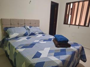 a bed with a blue and white quilt and a window at Casa charmosa, e bem localizada in Juazeiro do Norte