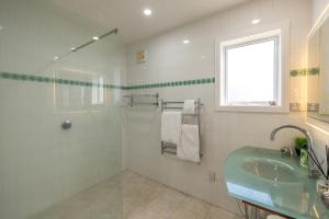 a white bathroom with a sink and a window at Premium Seaview Villa in Waiheke Island +43 photos