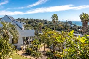 a house with palm trees and the ocean in the background at Premium Seaview Villa in Waiheke Island