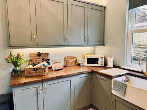 a kitchen with gray cabinets and a counter with a microwave at Moody House in Congleton