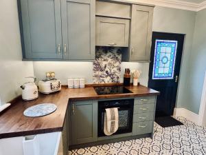 a kitchen with green cabinets and a counter top at Moody House in Congleton