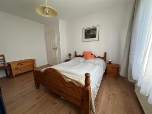 a bedroom with a wooden bed with an orange pillow at Ferienwohnung am Warnowhang in Kessin