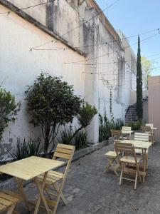 a row of wooden tables and chairs next to a building at Hostal Punto Americana in Guadalajara