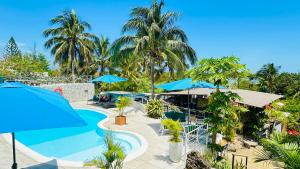 a swimming pool with blue umbrellas and palm trees at Residence Ma Vie Là Ltee in Le Morne