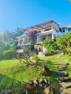 a house on a grassy hill with a garden at Residence Ma Vie Là Ltee in Le Morne