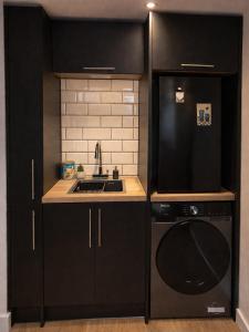 a kitchen with black cabinets and a sink and a dishwasher at 1 Bridge Rd in Cranleigh