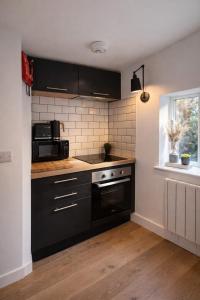 a kitchen with black cabinets and a black microwave at 1 Bridge Rd in Cranleigh