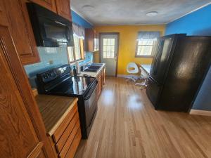a kitchen with a black refrigerator and wooden floors at Dracut Executive Rooms with Kitchen & Bath, Parking, Spacious & Comfortable in Dracut