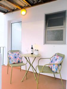 a table and two chairs and a table with a bottle of wine at Upstairs Home in Ponta Delgada