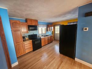 a kitchen with wooden cabinets and a black refrigerator at Dracut Executive Rooms with Kitchen & Bath, Parking, Spacious & Comfortable in Dracut +13 photos