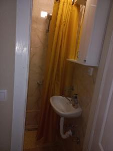 a bathroom with a sink and a shower with a yellow shower curtain at Velez IVANOVI DVORI in Jošanička Banja +5 photos