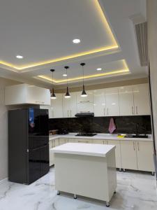 a kitchen with white cabinets and a black refrigerator at Novxanı Villa in Baku
