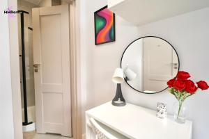 a bathroom with a mirror and a vase of red roses at MMRent Colorful Room in Gdańsk +6 photos