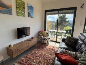 a living room with a couch and a flat screen tv at The Nest - cosy chalet for two in Jarjayes