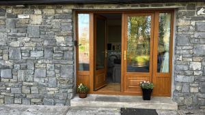a wooden door of a stone house with two plants at The Cuckoos Nest - 2 bedroom in Headford