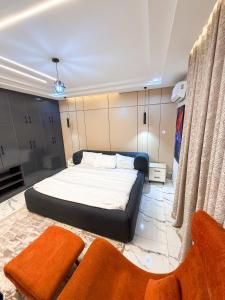 a bedroom with a bed and two chairs in it at Abuja Lux Apartment Wuye in Abuja
