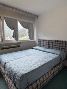 a bedroom with a bed and two windows at Casa Raggio di Sole in La Thuile +22 photos