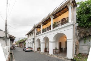 a street with white buildings and a car parked on the street at Arches Fort in Galle