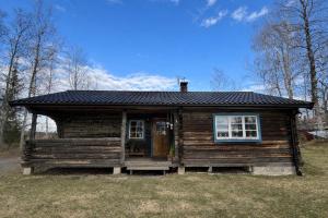 a small log cabin with a porch and windows at Mysig timmerstuga med sjötomt in Grangärde