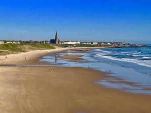 a beach with people on the sand and the ocean at Cosy Coastal Cottage in Tynemouth