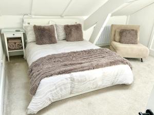 a bedroom with a large bed and a chair at Cosy Coastal Cottage in Tynemouth