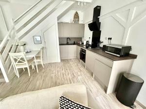 a white kitchen with a counter and a table at Cosy Coastal Cottage in Tynemouth
