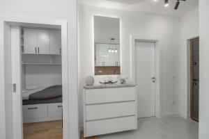 a white kitchen with white cabinets and a bed at Rajjan in Bar +11 photos