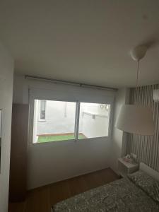 a bedroom with a window and a bed and a lamp at APARTAMENTO FELIP 1 in Burriana +4 photos