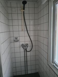 a shower with a hose in a white tiled bathroom at Woonwagen Carpe Diem in Oudwoude +30 photos