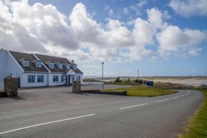 a large white house on the side of a road at Viking House Hotel Donegal in Kincasslagh