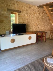 a living room with a tv on a white cabinet at Les choses de la vie in Saint-Alvère